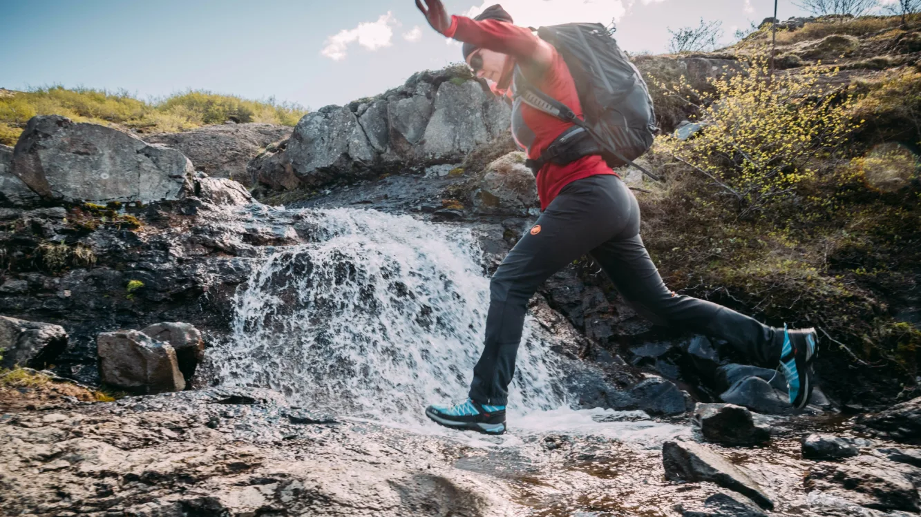 Unsere Kollegin Rita springt über einen Bach Mitarbeiterin von Katla Travel springt über einen Bach in Island